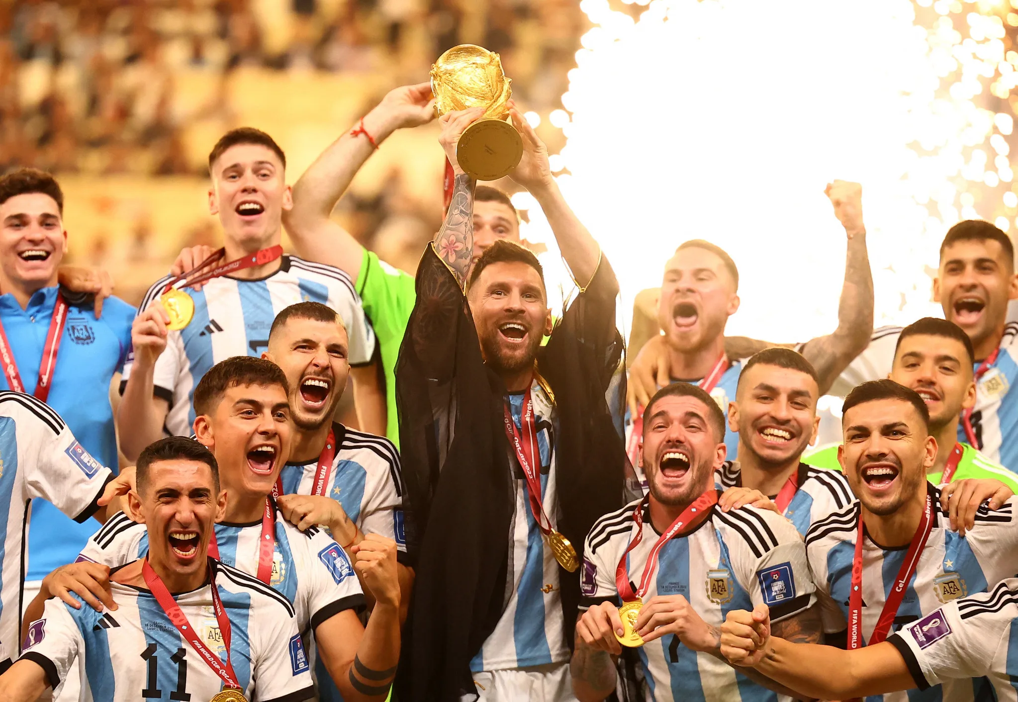 Lionel Messi lifts the World Cup trophy surrounded by celebrating Argentina teammates at the 2022 FIFA World Cup final