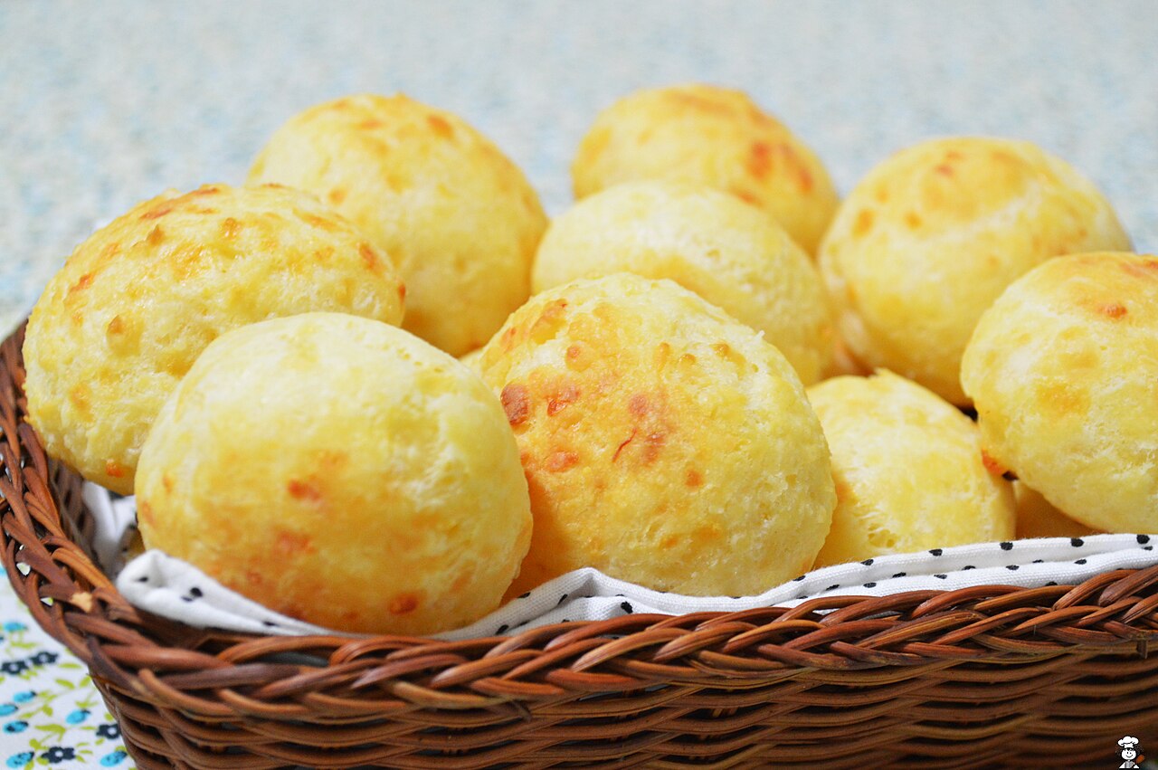 Pão de queijo — golden, puffed Brazilian cheese bread rolls arranged in a wicker basket lined with a cloth