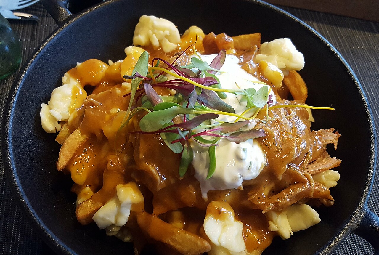 Poutine — crispy fries topped with cheese curds and rich brown gravy, served in a cast-iron pan