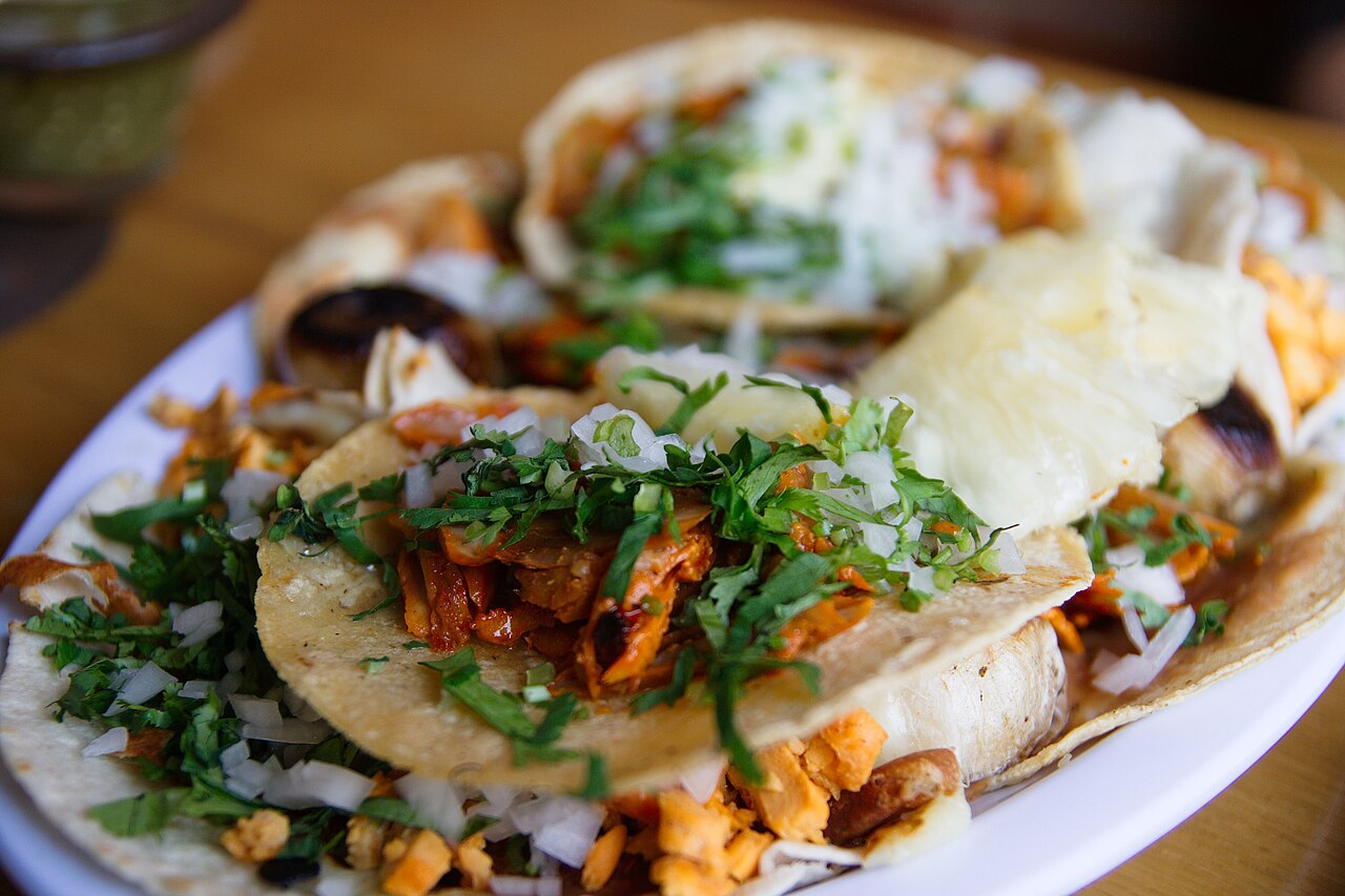 Tacos al pastor — marinated pork in corn tortillas topped with pineapple, white onion and fresh cilantro